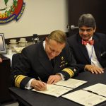 Deans Bitencourt and Thompson look on as Admiral Sievers signs